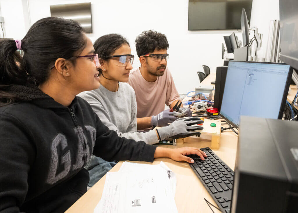 Three students working on a computer with building automation software.