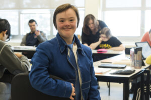 Academic Assistance for Adults with Developmental Disabilities student smiling in blue jacket in a classroom