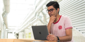 Student sitting at a desk reading on a laptop
