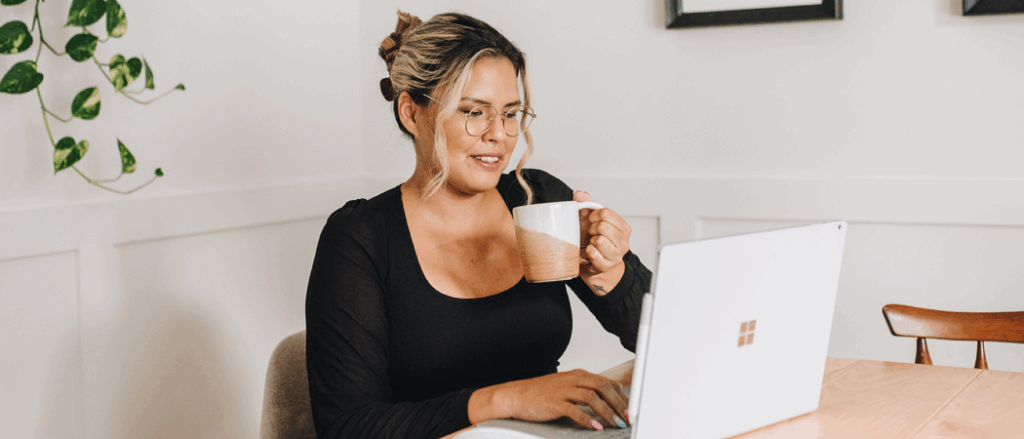 A young man drinking coffee and working on her laptop computer.