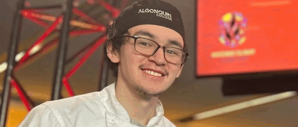 Joshua Qiyuk, a young Inuk man wearing a chef hat and coat, appears smiling.