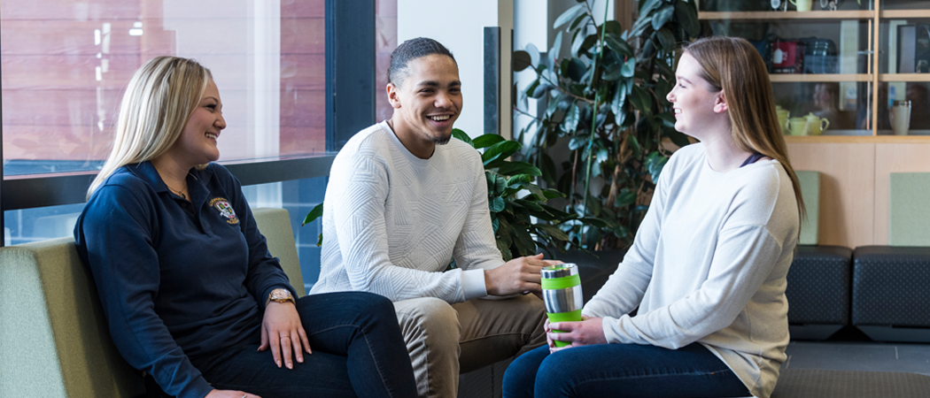 Three people sitting down, smiling, and chatting.