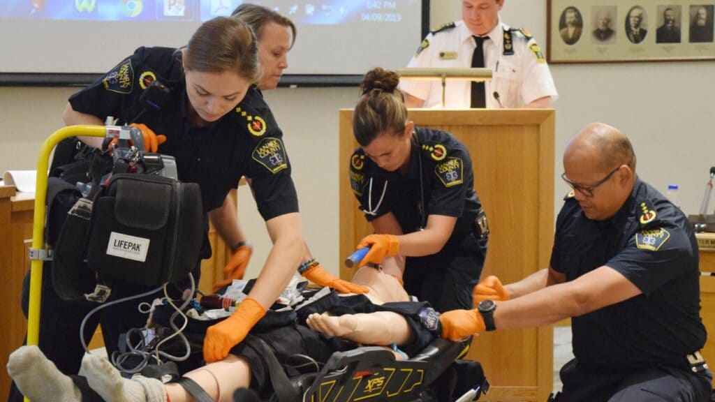 Four paramedics play out an advanced care scenario with a manikin, simulating treatment for a cardiac arrest.