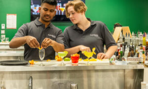 male and female Bartending students garnishing drinks