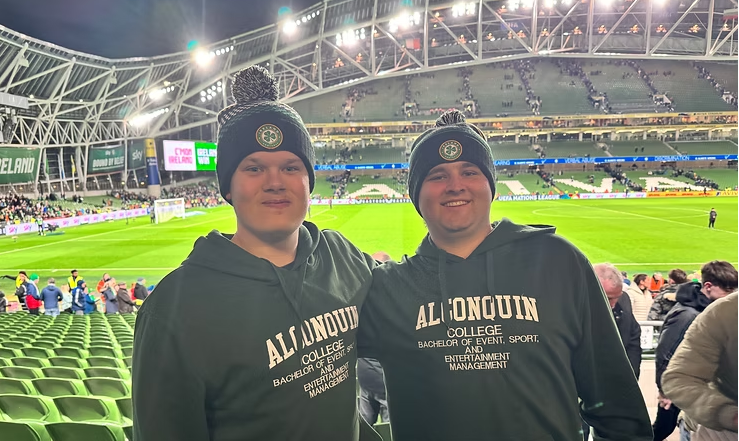 two male BESEM students in Ireland at soccer match with soccer field in background