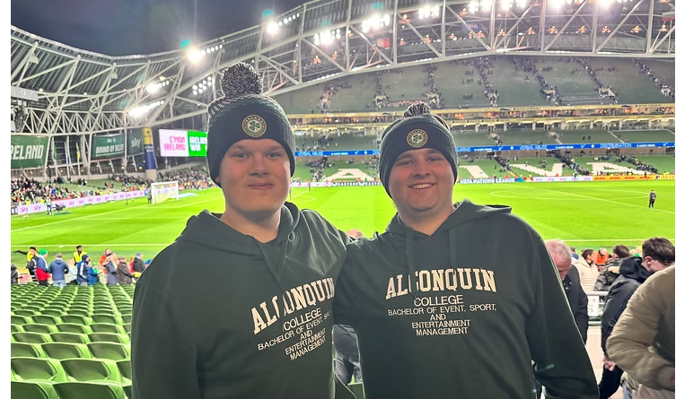 two male BESEM students in Ireland at soccer match with soccer field in background