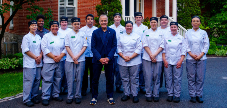 Culinary students in whites surround Prime Minister Mark Carney at Rideau Cottage