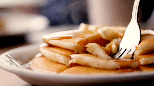 Animated GIF of a fork lifting up some warm pancakes with butter and syrup.