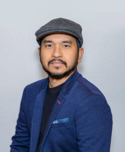 Headshot of a man wearing a blue blazer on a grey background 