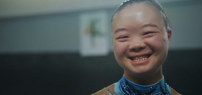 Photo of Kimana Mar smiling in her gymnastics outfit.