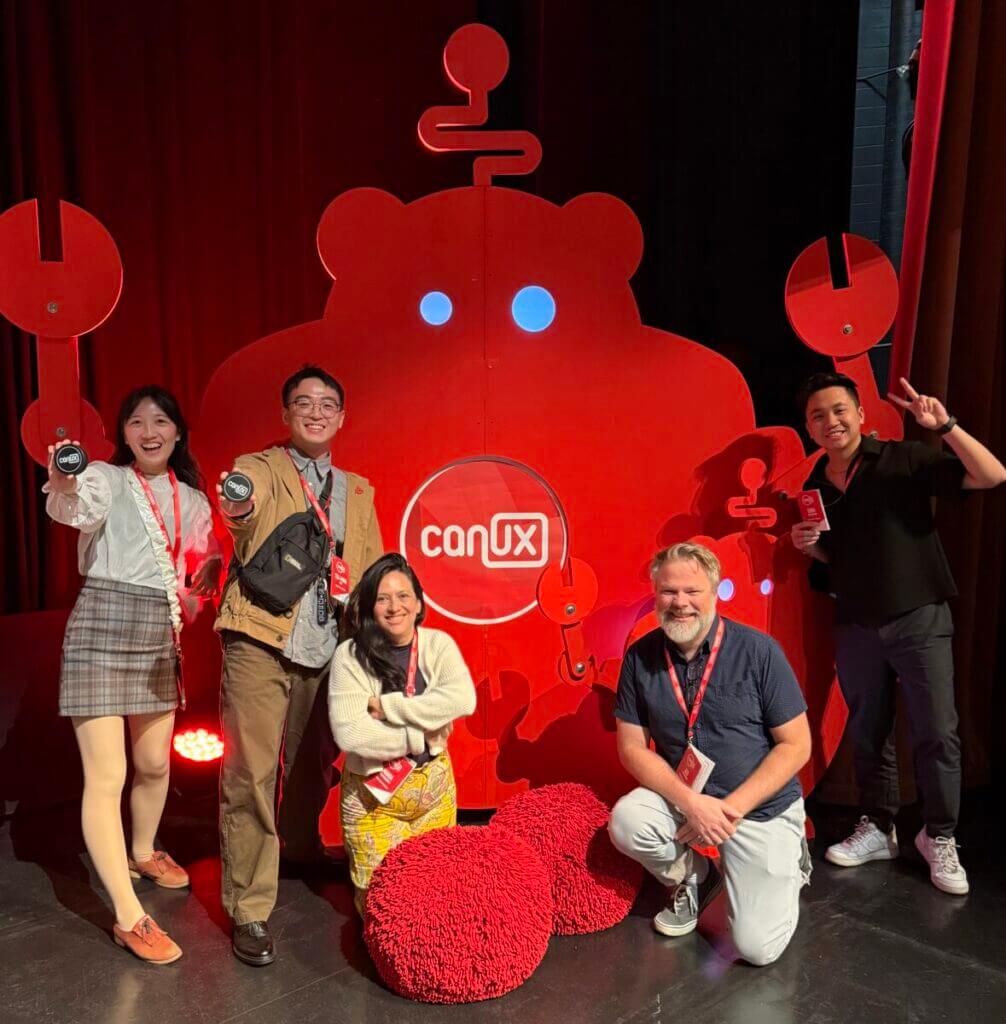 Five people pose in front of a red conference banner 