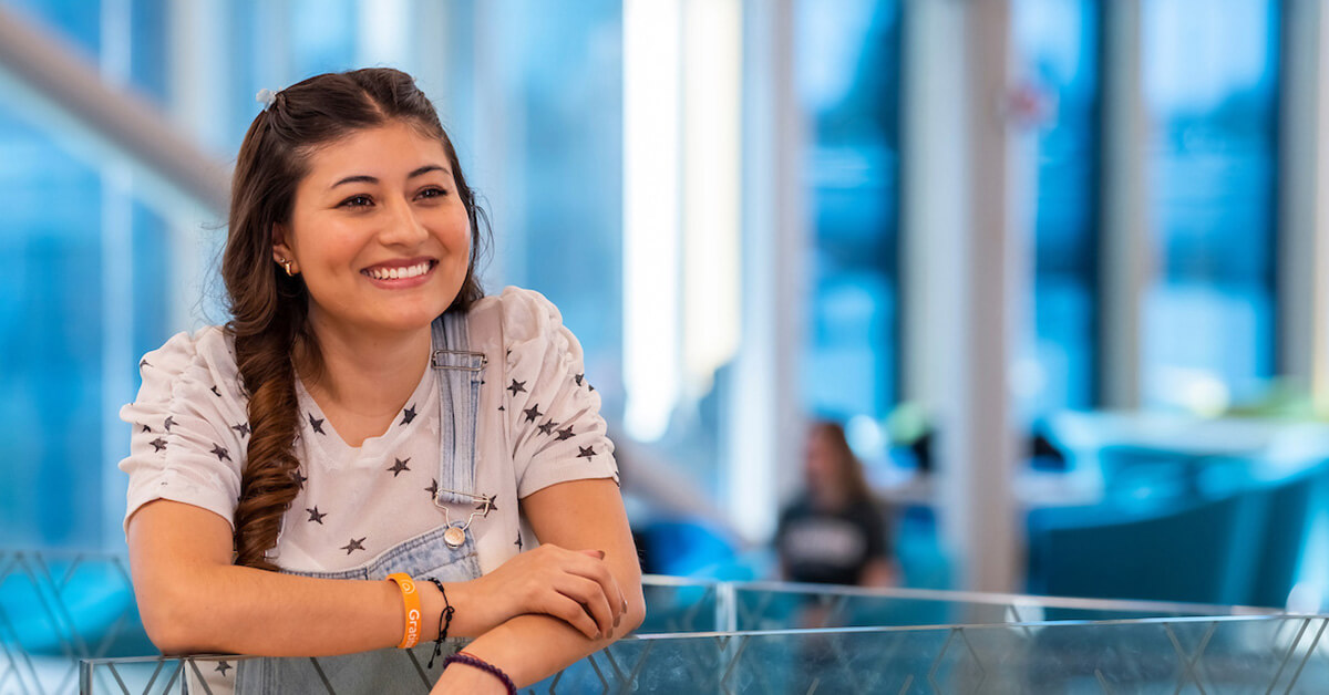 Female student with overalls looking off to the side in the Library.