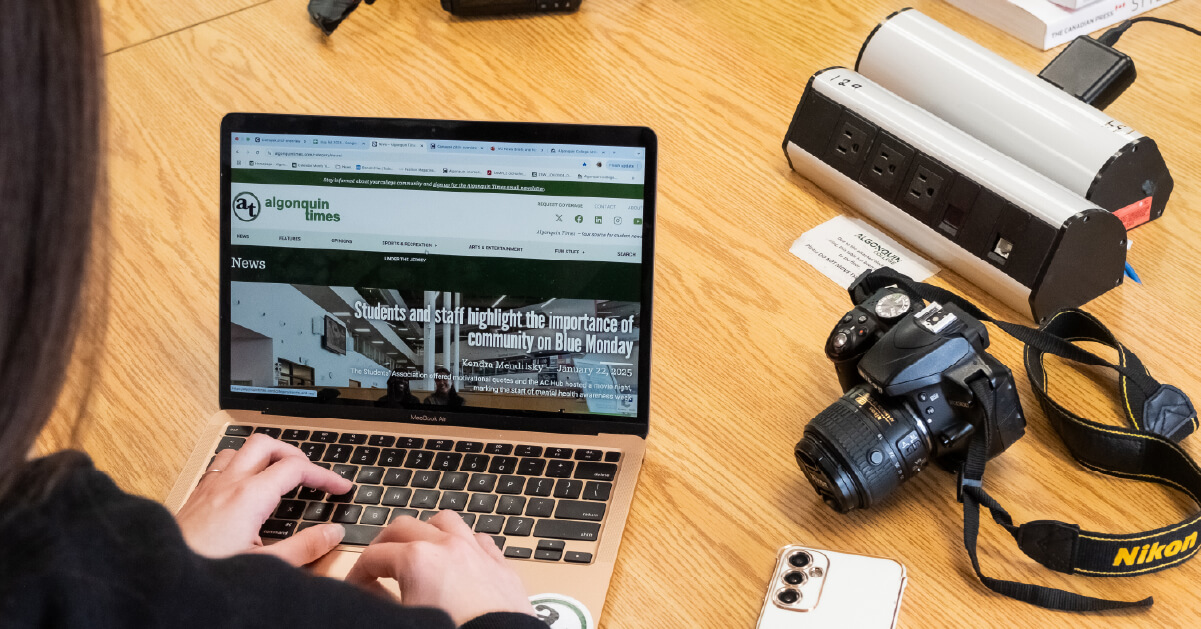 Student has laptop open to AlgonquinTimes website. Camera sits beside laptop.