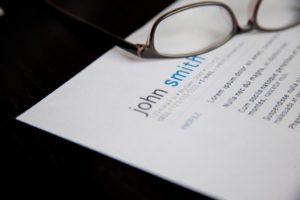 Photo of a pair of glasses sitting on a printed resume.