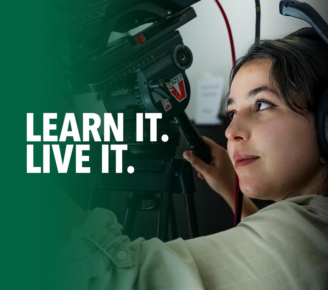 Student wearing a production headset while operating a professional video camera during hands-on media training.