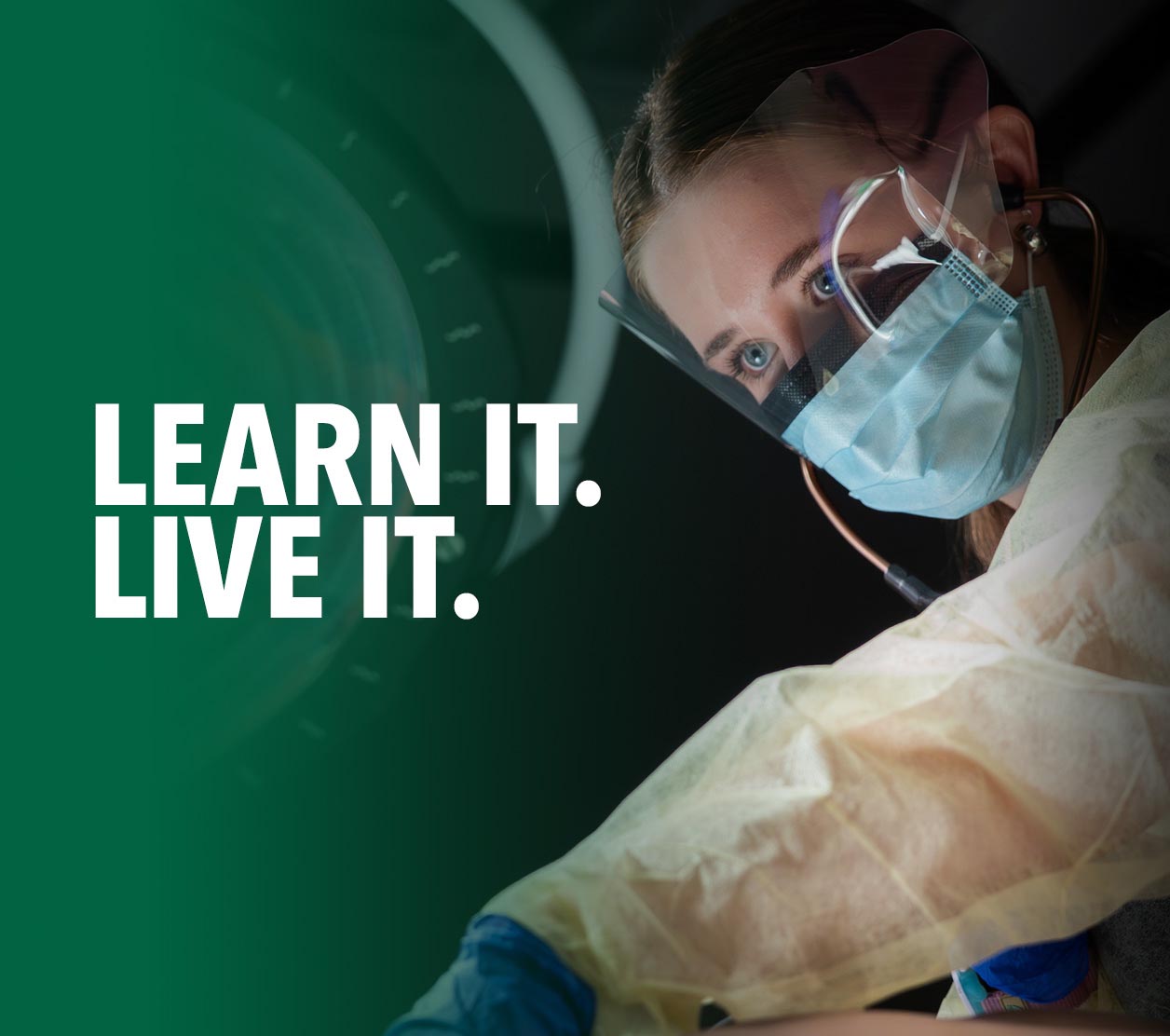 Dental student wearing a mask, face shield and protective gown while providing hands-on patient care in a clinical training environment.