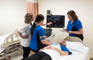 students and professor in the sonography lab practicing taking images of internal organs on a patient