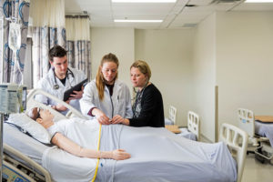 Nursing professor demonstrating skill to students in health lab