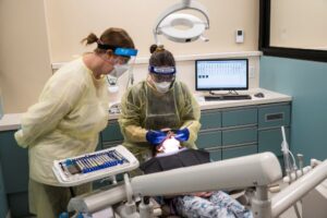 professor monitoring a student practicing dental hygiene skills on a patient
