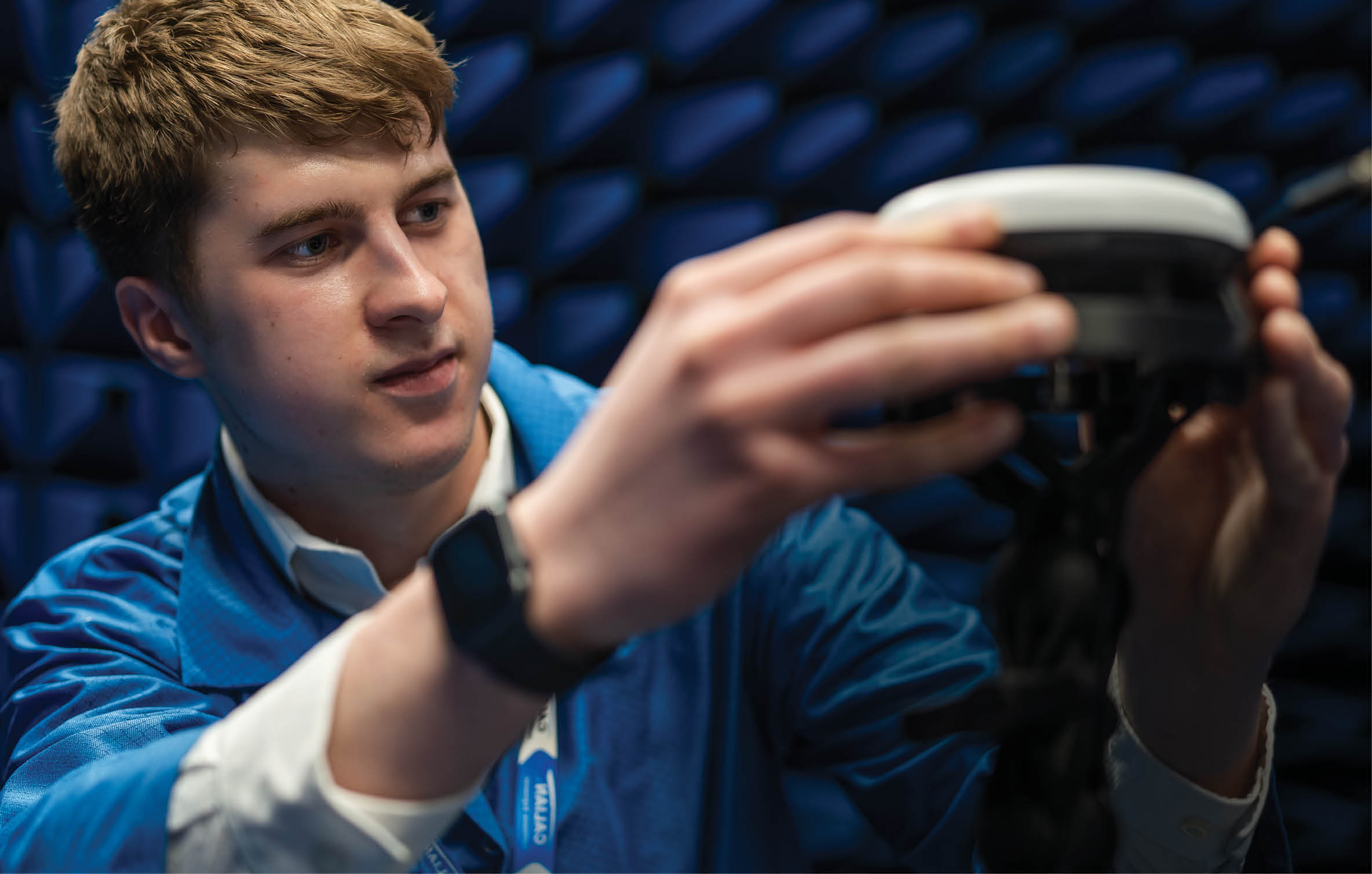 A man in a blue jacket is holding a device, possibly a video game controller, while looking at a screen. AI generated content