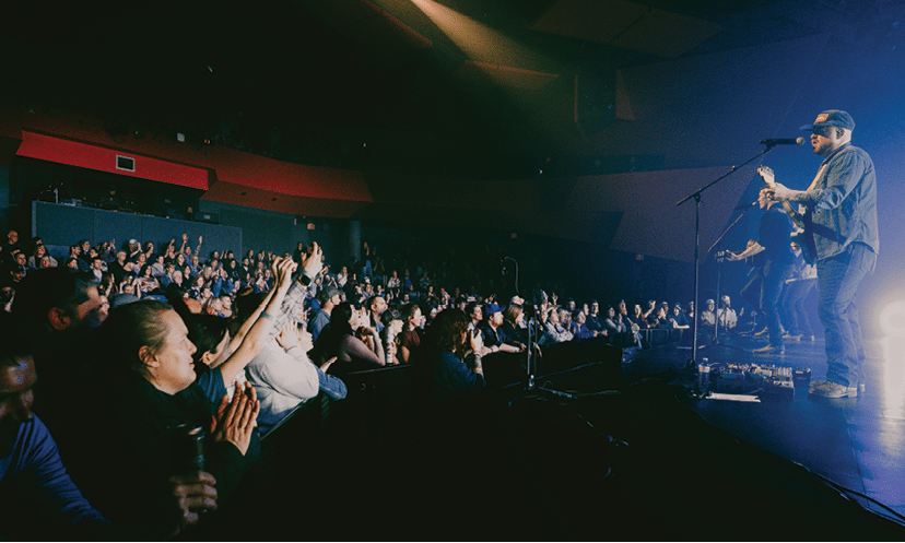 A man is singing on stage in front of a large crowd. AI generated content