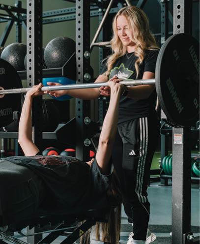 Two people are in a gym, one is lifting weights and the other is on a bench. AI generated content