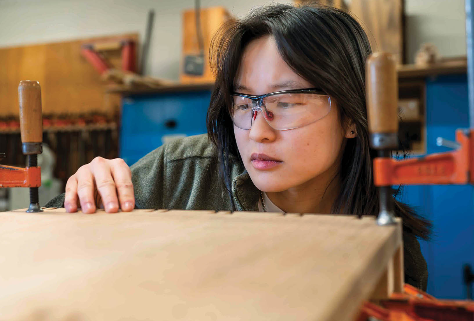 A woman wearing glasses is working on a wooden object, possibly a piece of furniture. AI generated content