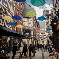 A street scene with a variety of umbrellas and people walking. AI generated content