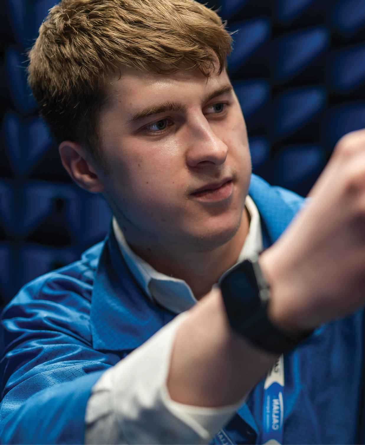 A man in a blue jacket is holding a device, possibly a video game controller, while looking at a screen. AI generated content
