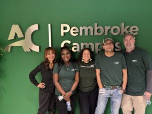 The Information Security and Privacy team standing in front of a Pembroke Campus sign.