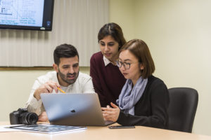 three students looking at a laptop