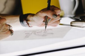Photo of person drawing with a pencil on paper - on top of a lightbox.