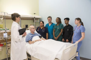 Nursing students with a patient and instructor in a hospital setting.
