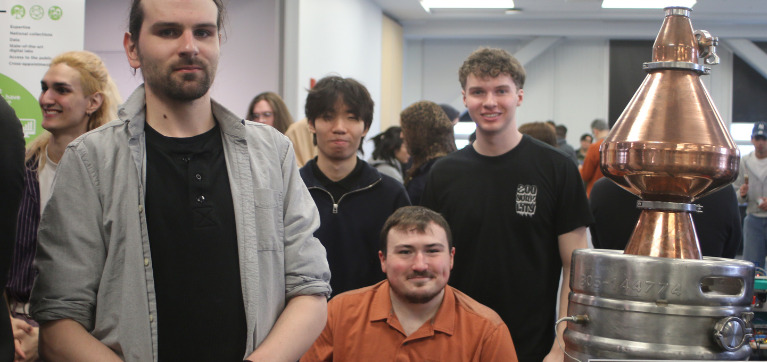 A group of engineering students gather for a photo with their distillation project.
