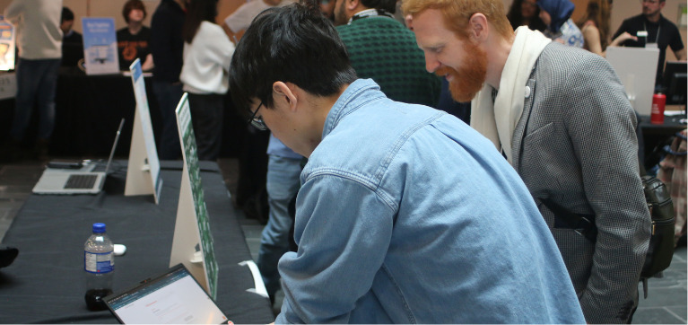 A student explains their project to an Algonquin College staff member.