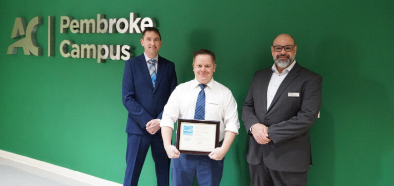 Graham Timperon, Building Performance Analyst (left), Brendan Murray, Manager, Facilities and Operations, Pembroke Campus and Mohamed Zeid, Senior Project Manager (right), part of the team behind the certification, show off the plaque from Natural Resources Canada that will be displayed in Pembroke.
