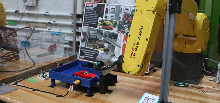 Robotic arms demonstrating a system to elevate cars. Toy cars are used for scale.