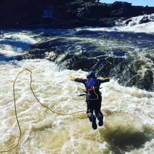 Student in a wetsuit with tether, diving into the swift water - on Frequently Asked Questions page