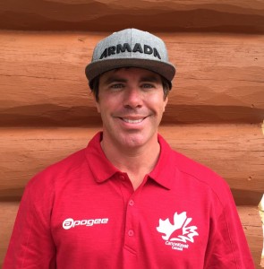 Ryan wearing a red shirt standing in front of a log building