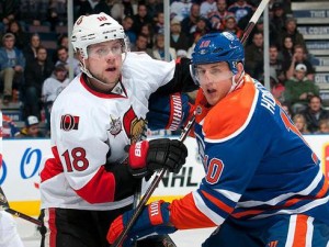 Ottawa Senators hockey player holding off an Edmonton Oilers player on the ice. 
