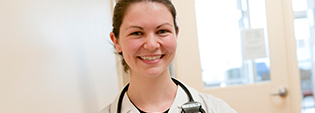A young woman with a stethoscope around her neck smiling