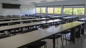 Rows of tables and chairs with windows facing the Ottawa River, TVs on the wall in the back of the class.