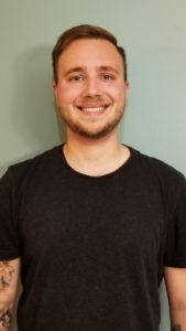 Head shot of a man smiling on a beige background.