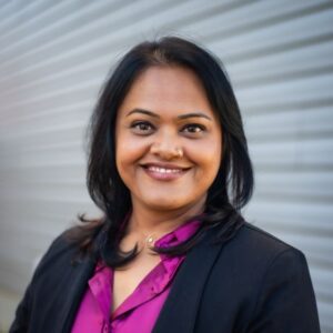 Head shot of a woman smiling on a gray background.