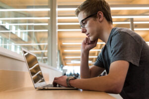Student using a laptop on a wide wooden counter.