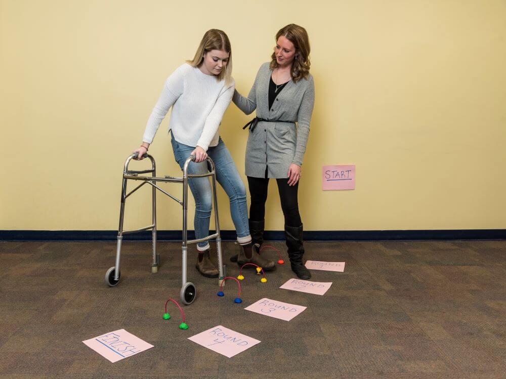 Therapeutic Recreation student and professor simulating a mobility activity in class
