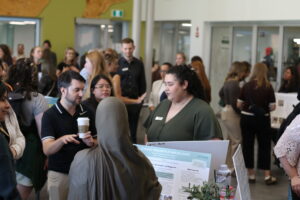 People gathered around talking in a room around table displays.